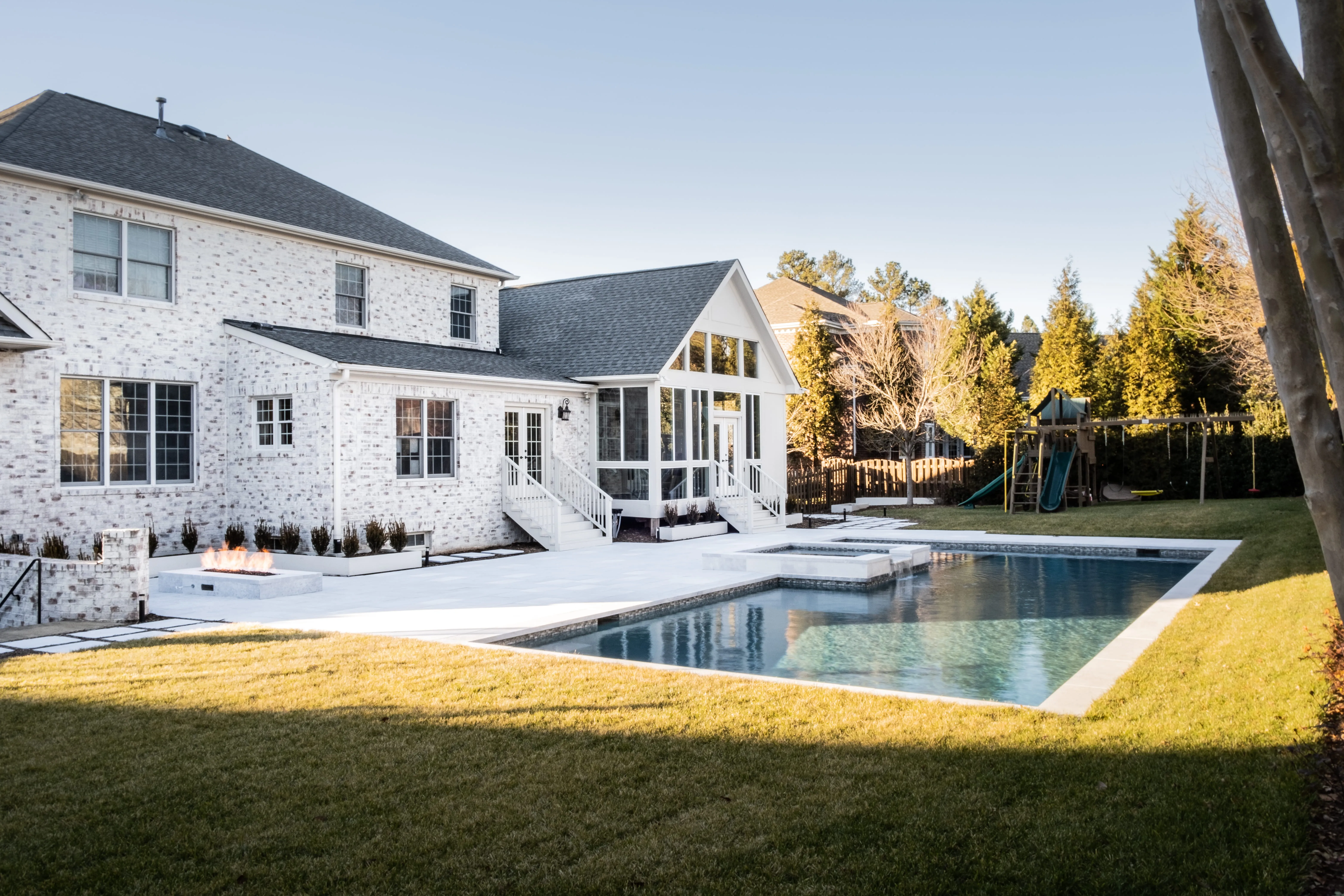 A stunning luxury backyard transformation in Raleigh, NC, by Currin Outdoor Living, featuring a modern inground swimming pool, custom patio lounge area, and professional landscape design.
