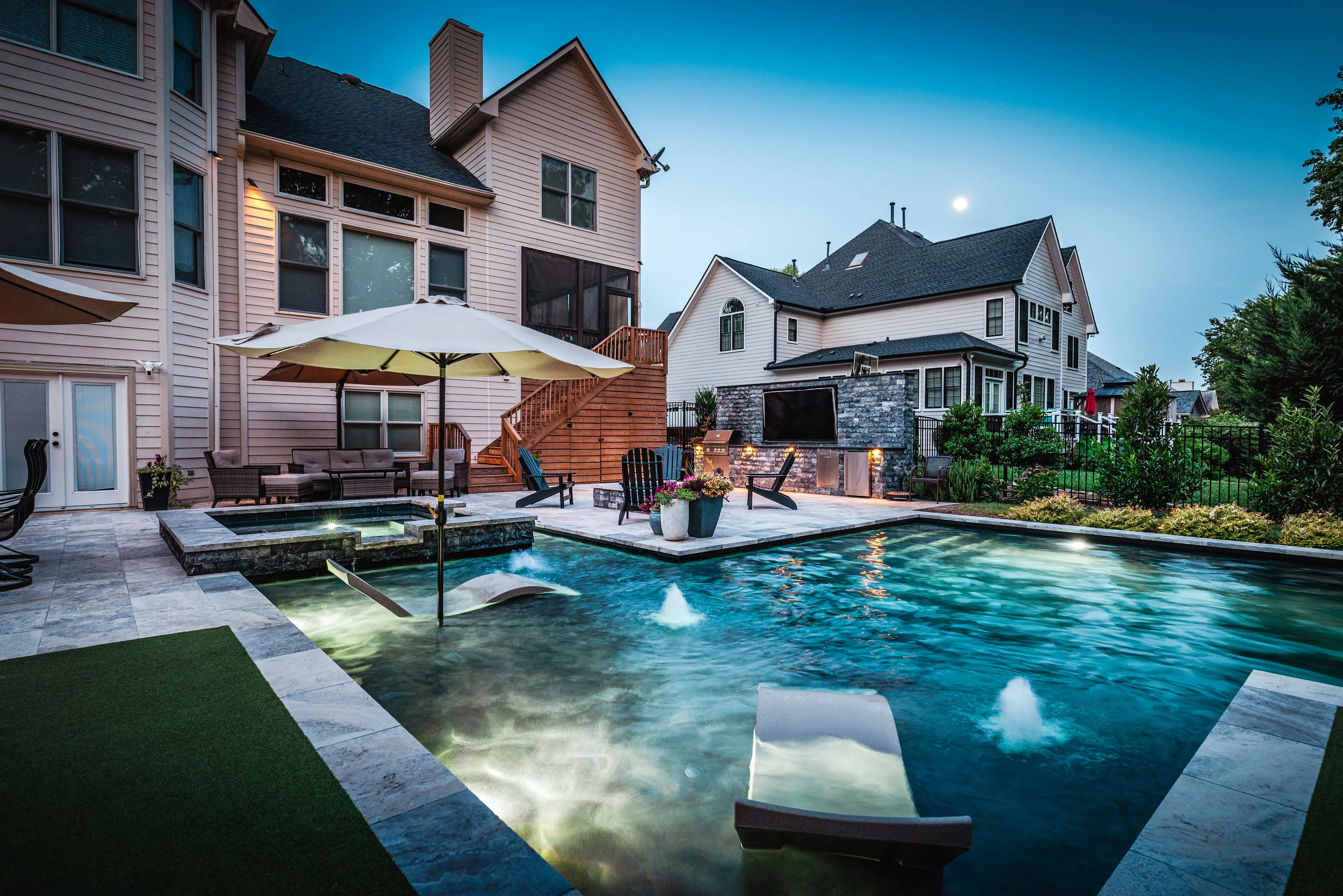 A stunning luxury inground pool installation by Currin Outdoor Living, featuring integrated water features, professional patio hardscaping, and a resort-style lounge area in a private Raleigh, NC backyard.