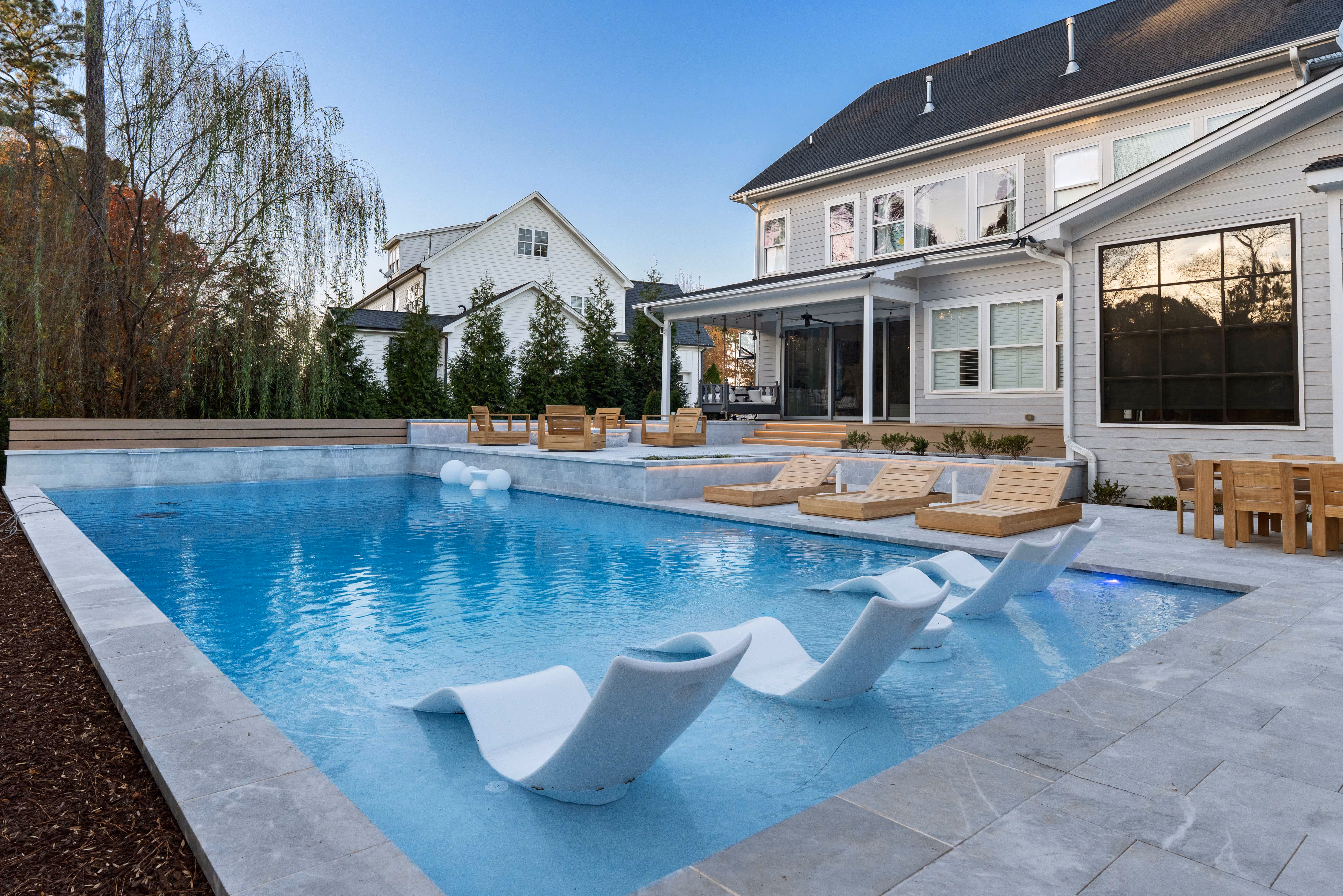 A premier residential pool design by Currin Outdoor Living, showcasing crisp geometric lines, integrated spa features, and professional hardscape decking in a private Raleigh, NC estate.