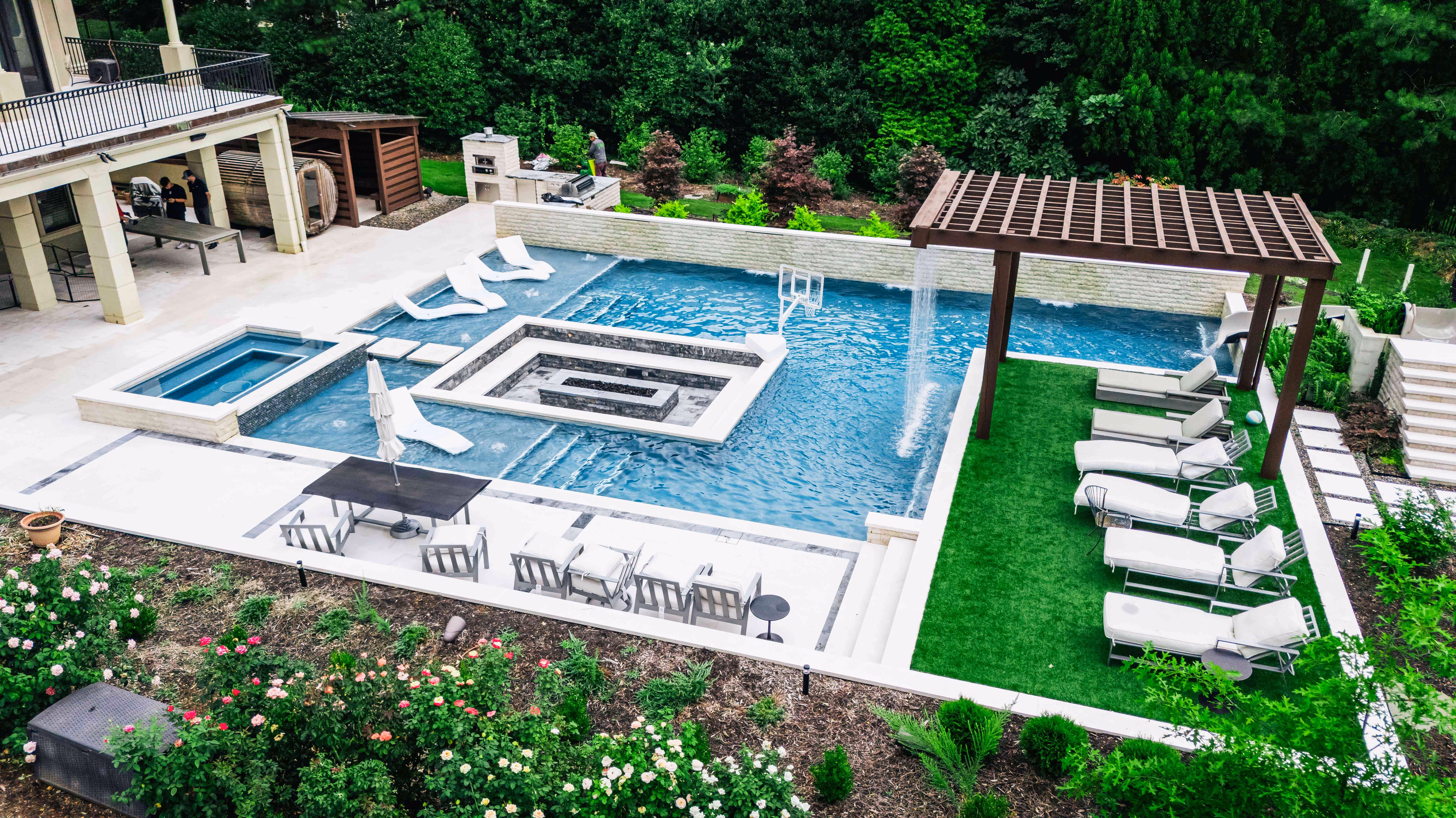 A beautiful, modern backyard design by Currin Outdoor Living, featuring a custom inground swimming pool, integrated patio lounge area, and professional landscape installation in Raleigh, NC.
