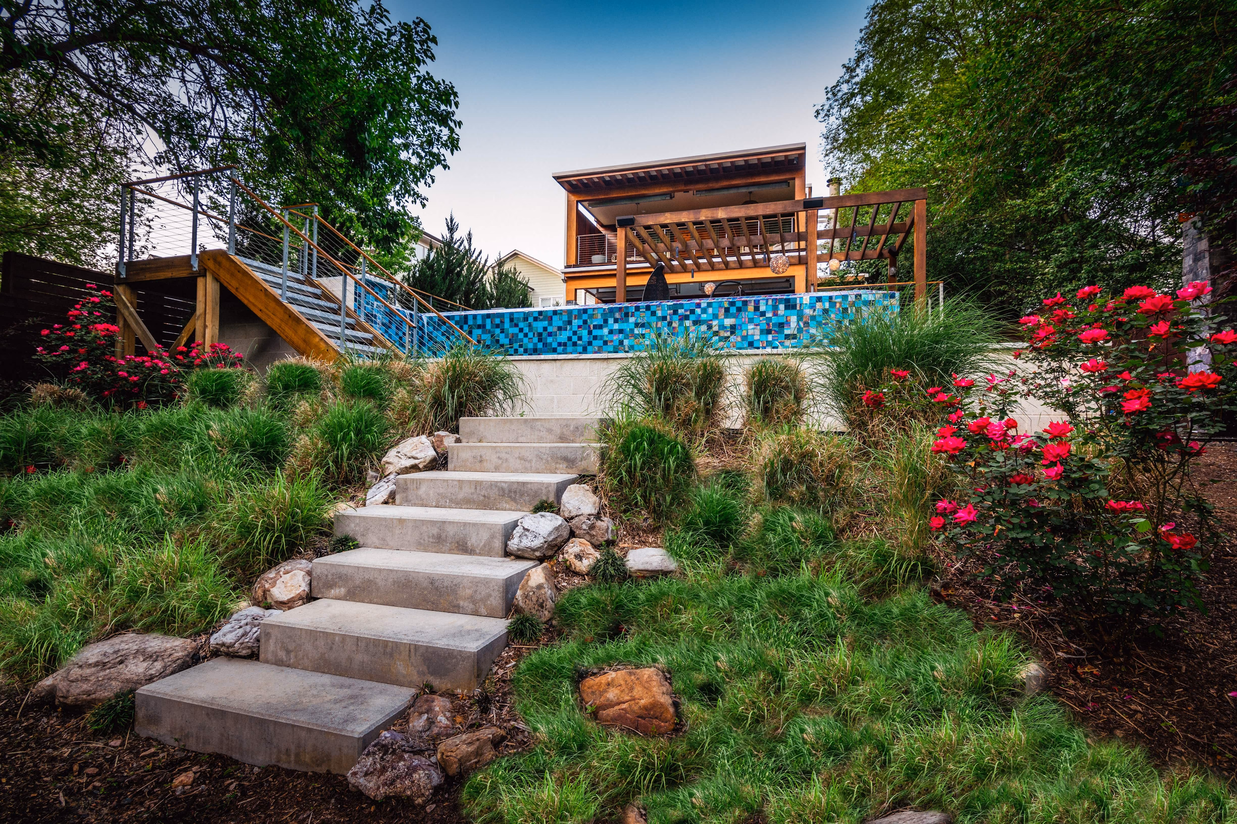 Eye-level view of a luxury residential backyard featuring professional landscape design, stone pathways, manicured garden beds, and custom outdoor lighting built by an outdoor living company in Raleigh, NC.