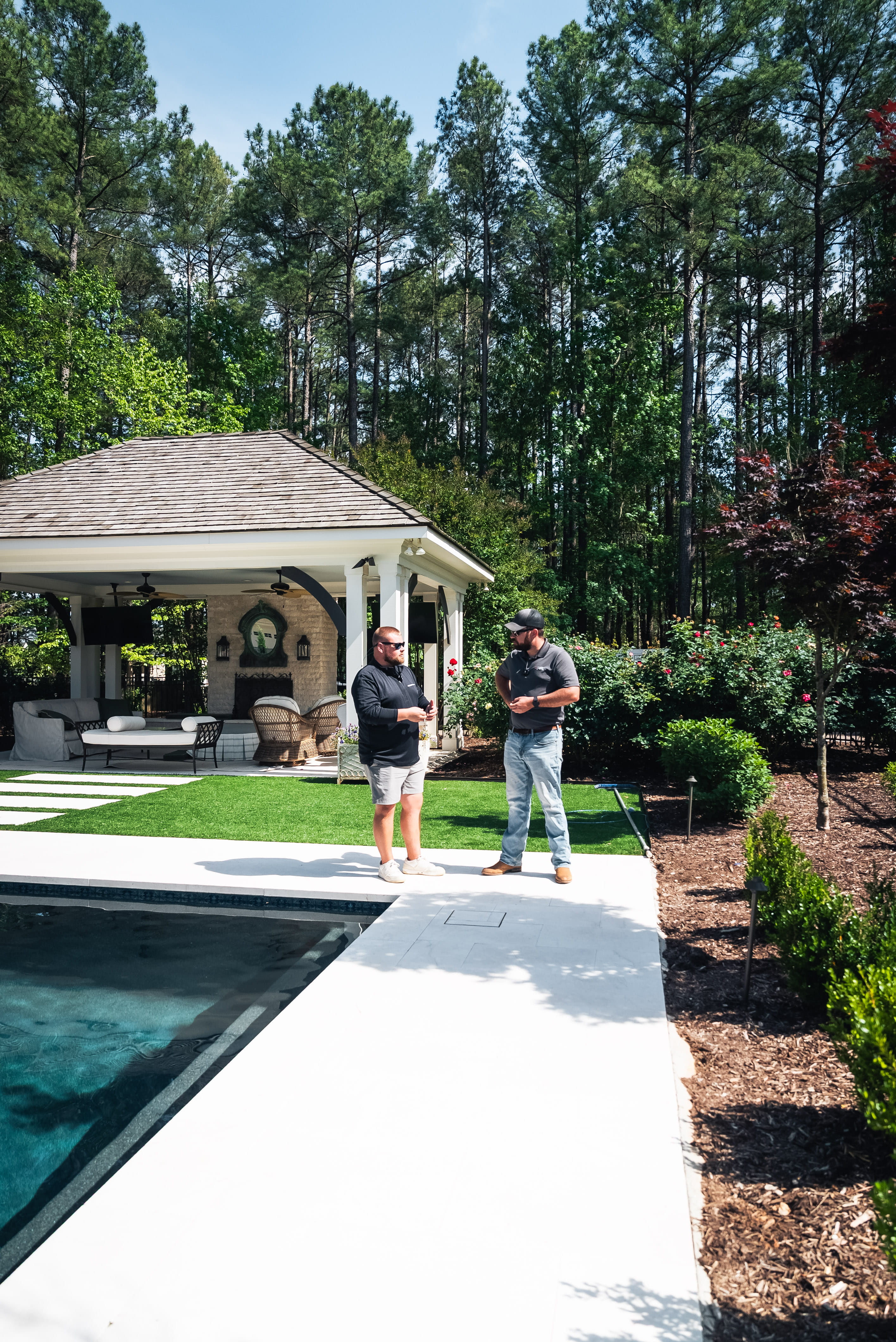 A luxury concrete pool build featuring a custom backyard cabana and pavilion designed by a pool builder in Raleigh, NC. Currin Outdoor Living