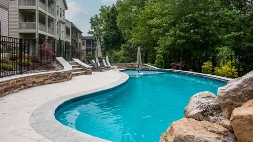 A luxury custom inground swimming pool with clean blue water and a stone patio surround built by a premium pool builder in Wake Forest, NC.