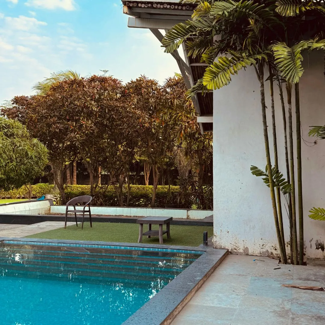 Custom inground swimming pool featuring clear blue water, light patio coping, white architecture, and lush surrounding landscaping in Garner, NC.