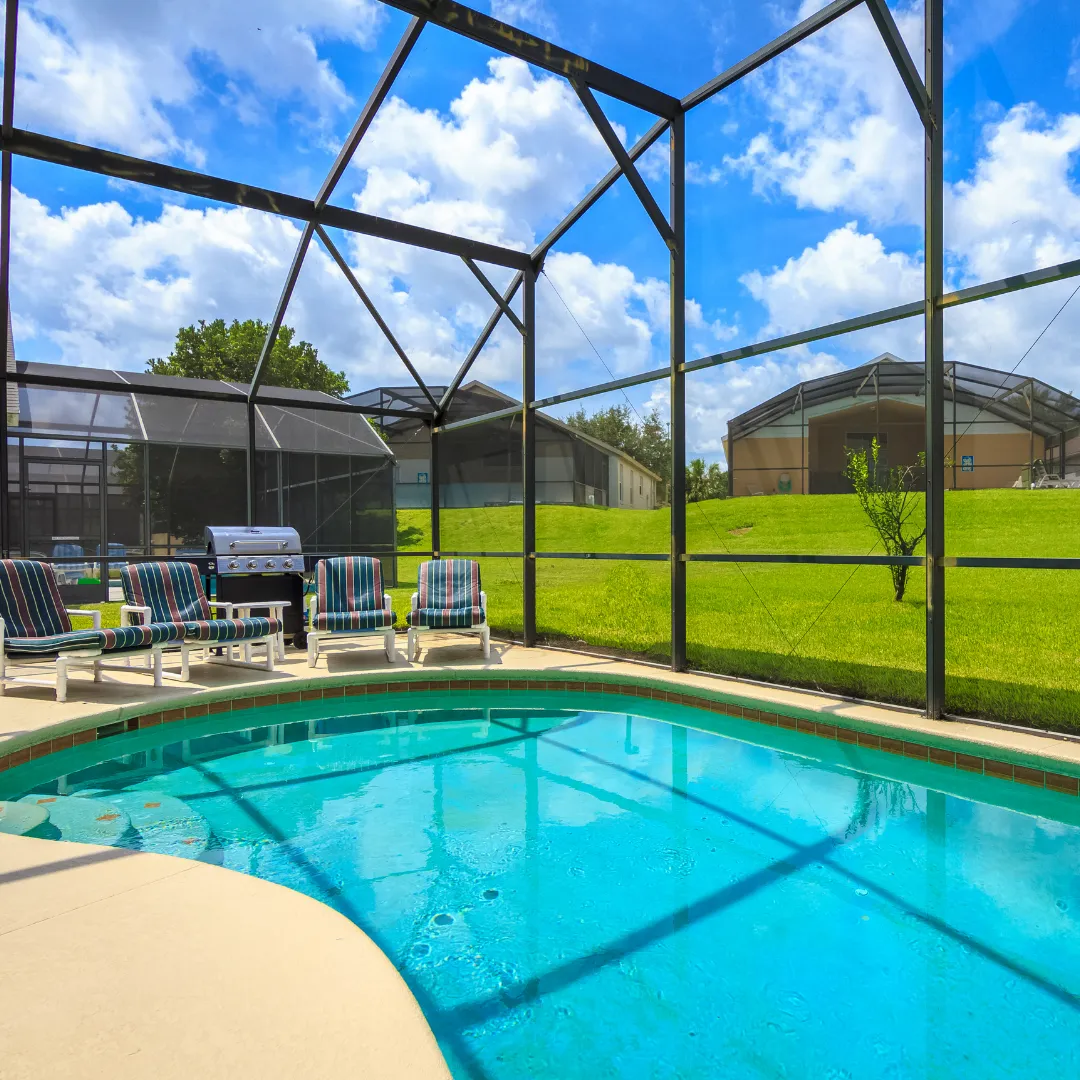 Custom curved inground swimming pool inside a glass or screen enclosure cage with concrete patio seating in Raleigh, NC.