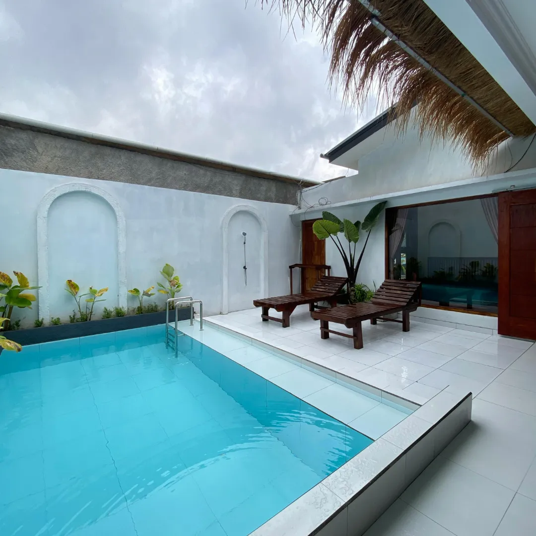 Modern minimalist inground swimming pool featuring turquoise water, clean white tile patio surround, and tropical palm tree landscaping in Raleigh, NC.