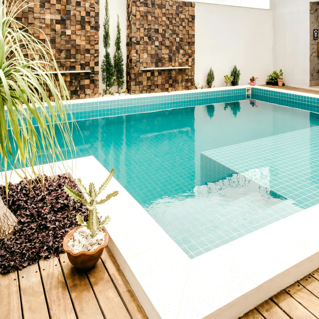 Compact custom plunge pool featuring turquoise water, wood deck coping, and modern stone wall accents in Raleigh, NC.