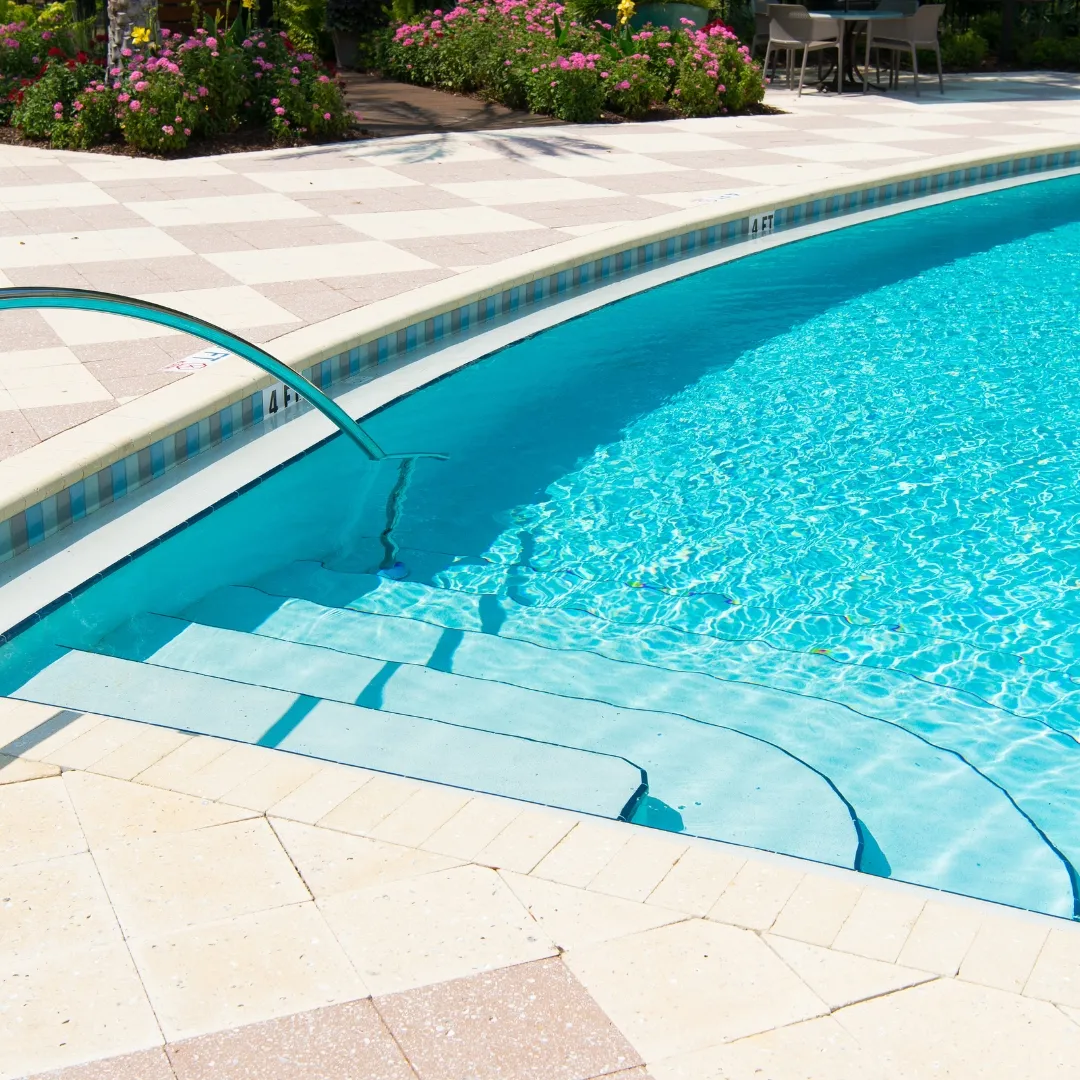 Inground swimming pool entry steps with clear blue water and custom stone coping in Raleigh, NC.
