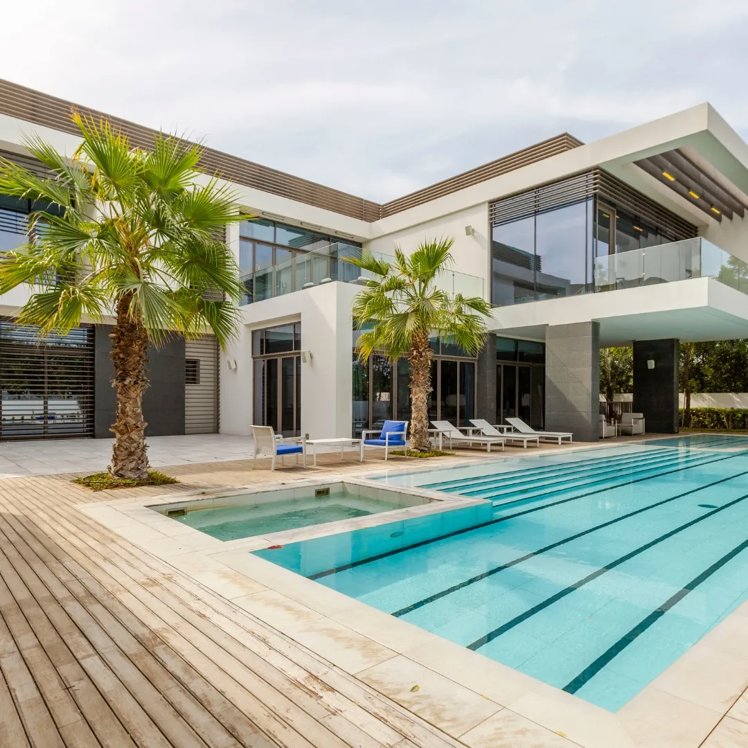 Luxury modern backyard featuring a rectangular inground swimming pool, wood plank patio decking, lounge chairs, and palm tree landscaping in Raleigh, NC.