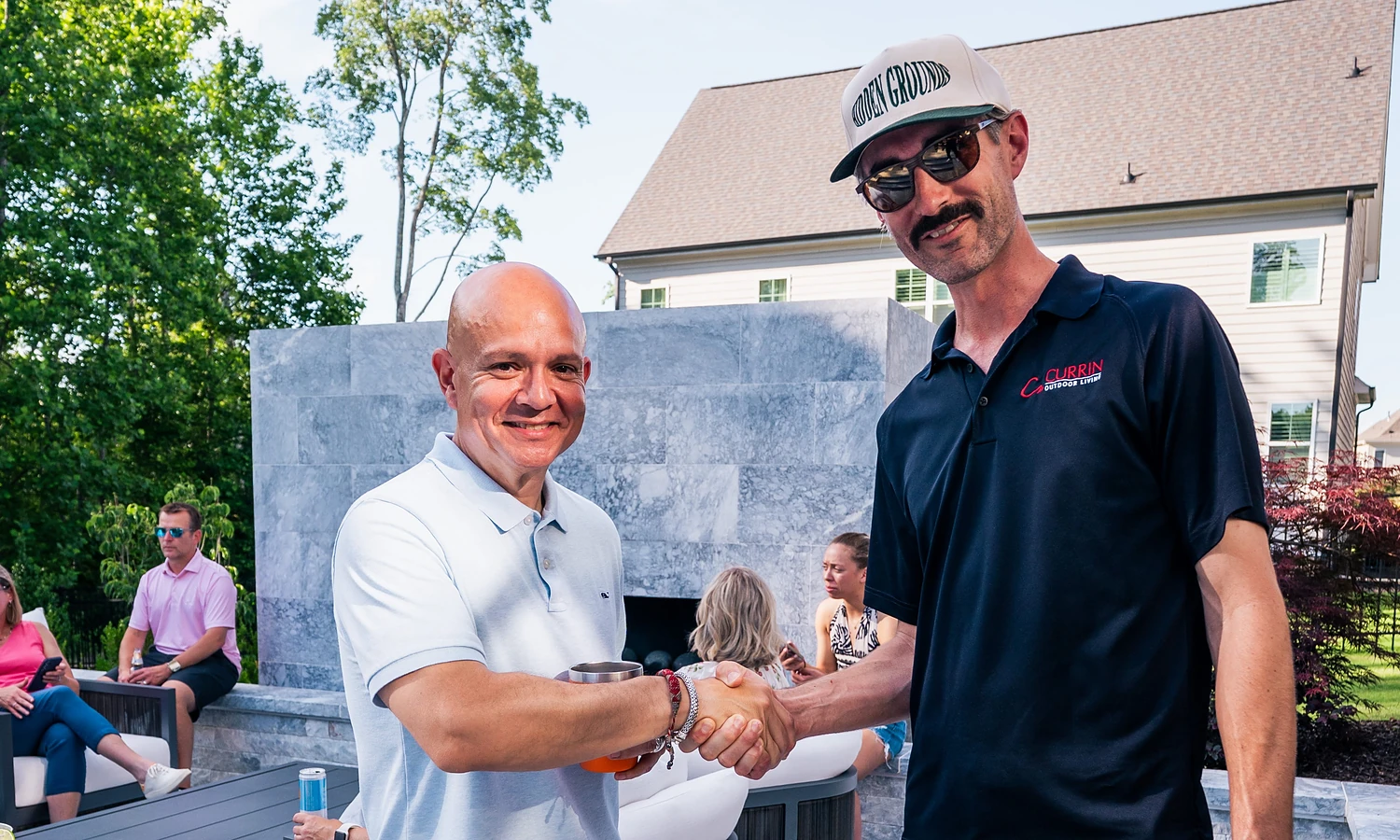 An outdoor living designer shaking hands with a satisfied client in a Raleigh NC backyard