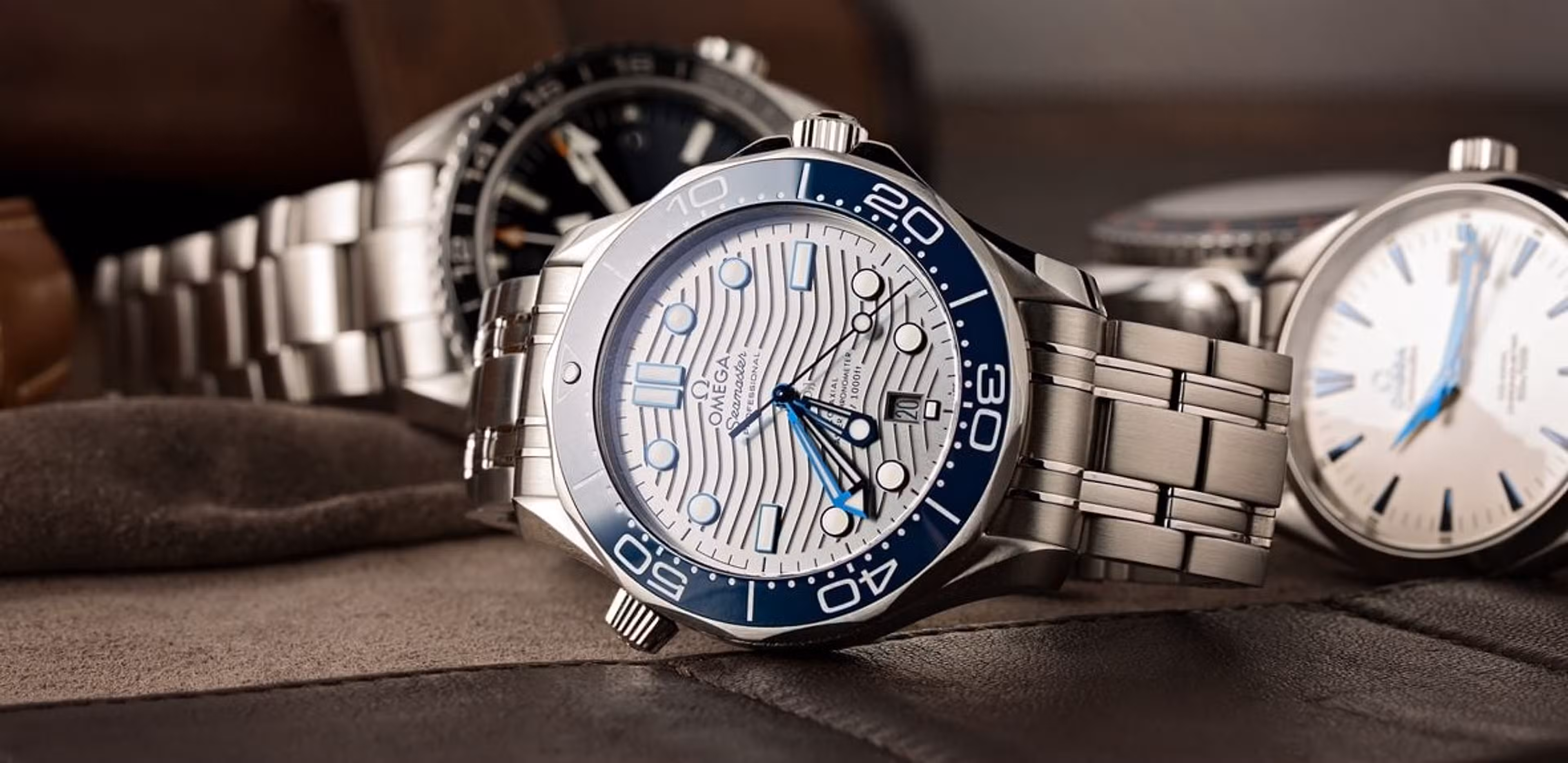 an omega seamaster sitting on a tabletop alongside a few other omega watches