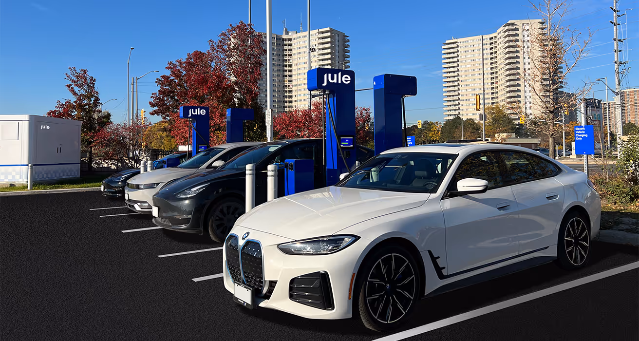 Four electric vehicles charging at Jule chargers with Jule's energy storage system in the background. 