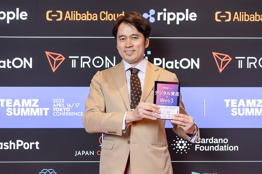 ベージュのスーツを着た男性が、デジタル資産とWeb3に関する本を両手で持っている。