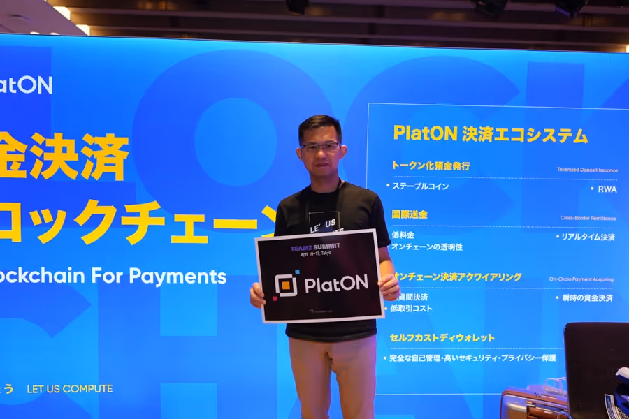 PlatONのロゴが描かれた看板を持つ男性が、青い背景のPlatON決済エコシステムの説明ボードの前に立っている。