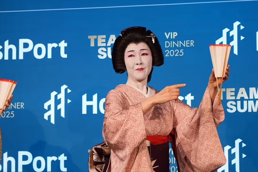 扇子を持ち、伝統的な着物と髪型で舞台で踊る日本舞踊の女性。