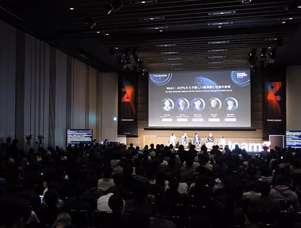多くの聴衆が参加する会議で、5人のパネリストがステージでWeb3に関する討論を行っている。
