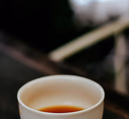 木のテーブルの上に置かれた白い湯のみ茶碗に入った茶。