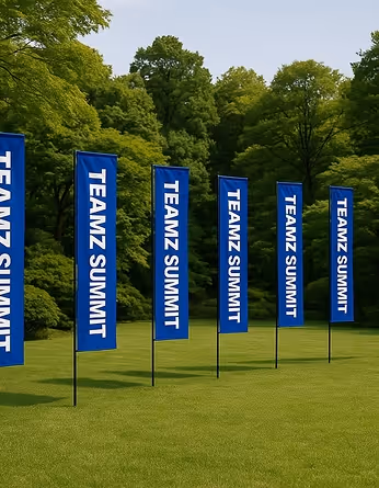 青い背景に白でTEAMZ SUMMITと書かれた6つの縦長の旗が芝生の上に並んで立っている。