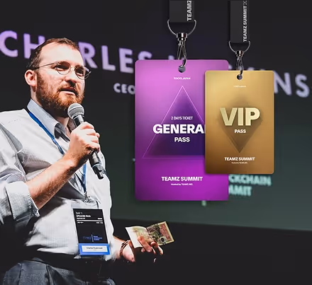 マイクを持ち、名札と現金を手にした男性がチームZサミットの一般とVIPパスを背景に話している。