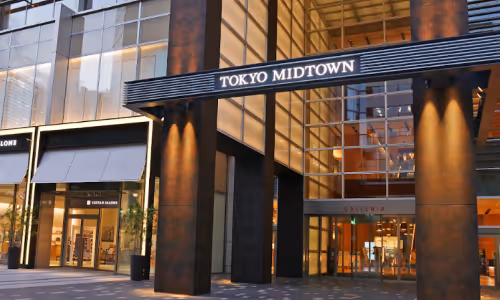 夜の東京ミッドタウンの入り口、ガラス張りの建物と看板が見える。