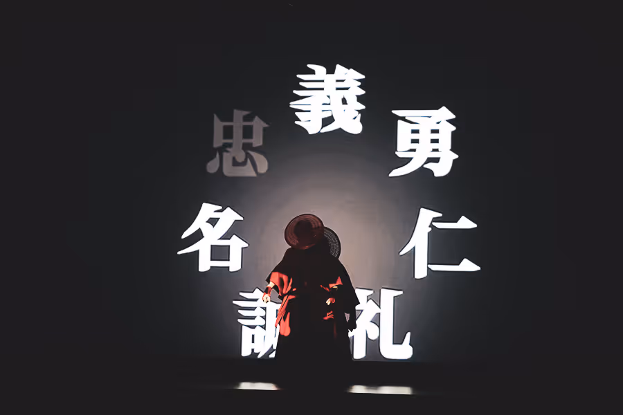 背を向けて立つ人物の周囲に大きな白い漢字の文字が浮かび上がっている様子。