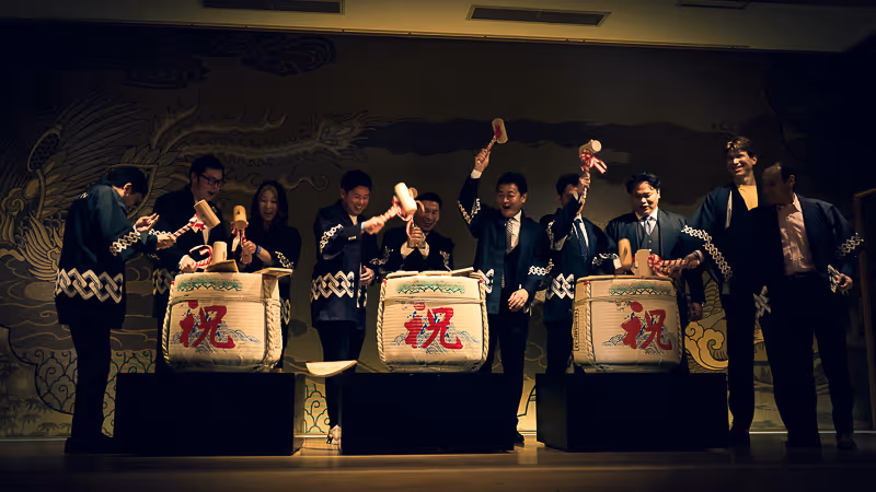 和服を着た人々が大きな樽酒を木槌で割っている日本の祝いの儀式。