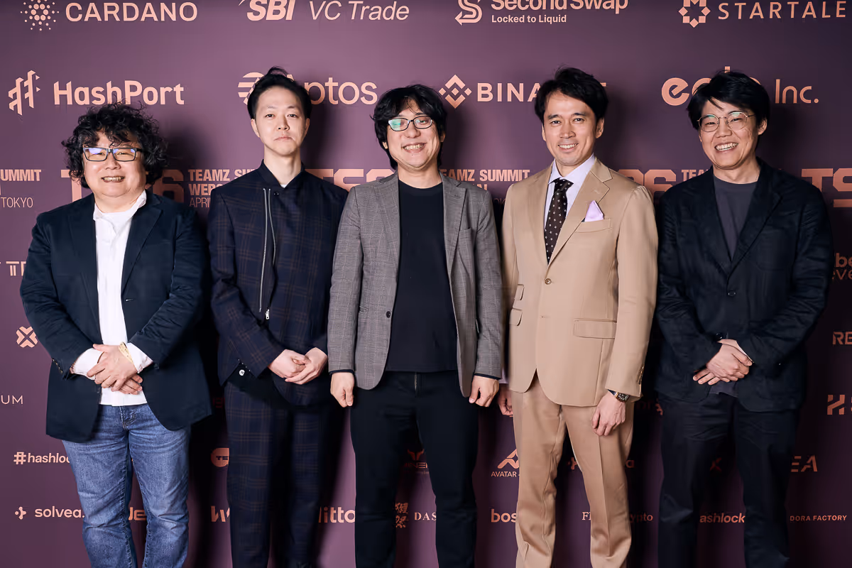 5人の男性がビジネスイベントの背景前で並び、カジュアルからフォーマルな服装で笑顔を見せている。