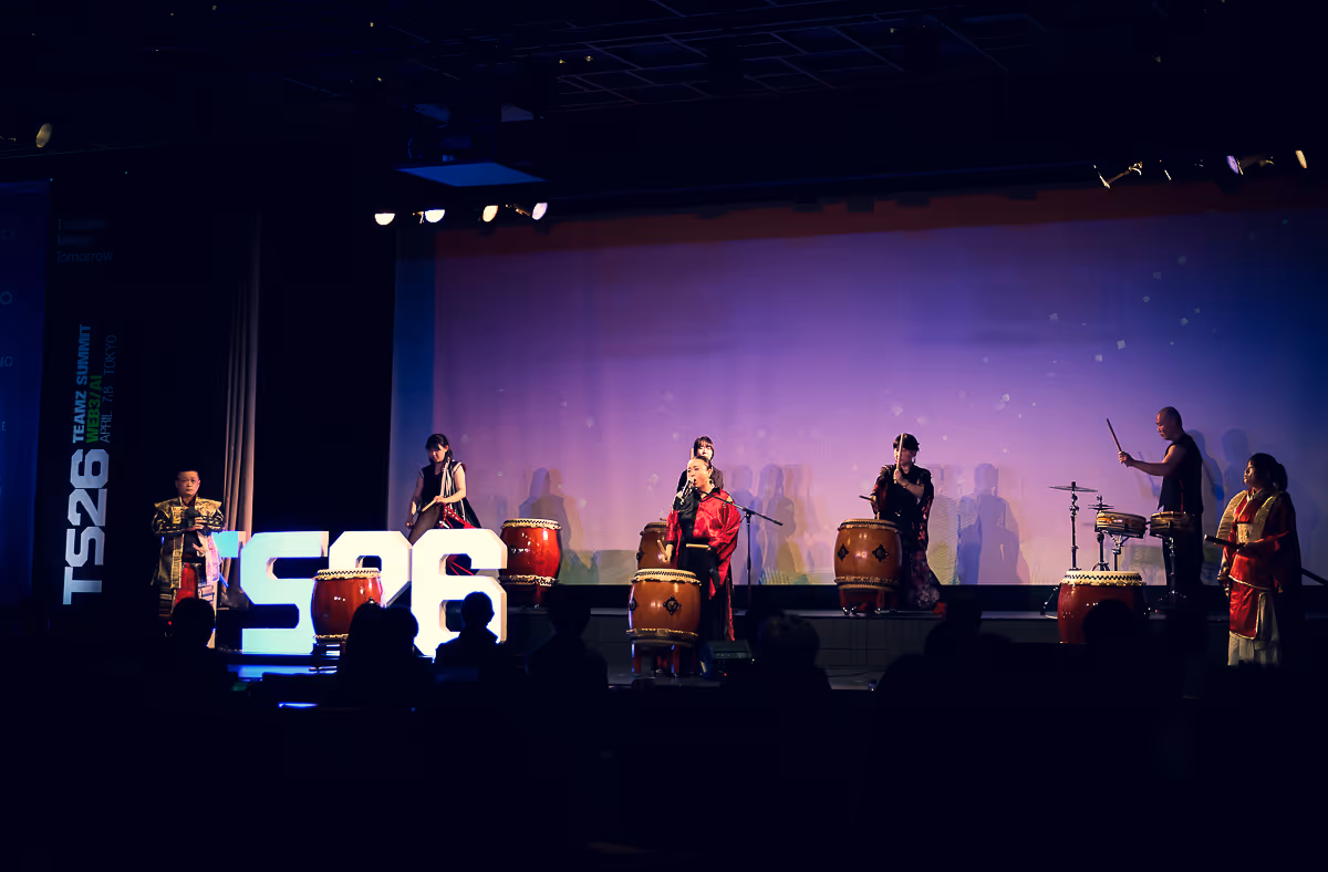 伝統的な和太鼓を演奏するグループが暗いステージでパフォーマンスをしている。