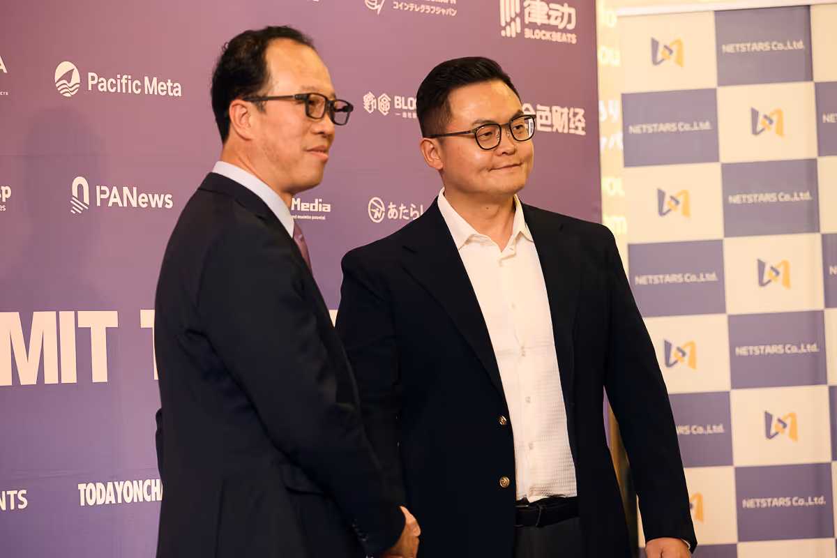2人の男性が紫色の背景の前で握手を交わしている。