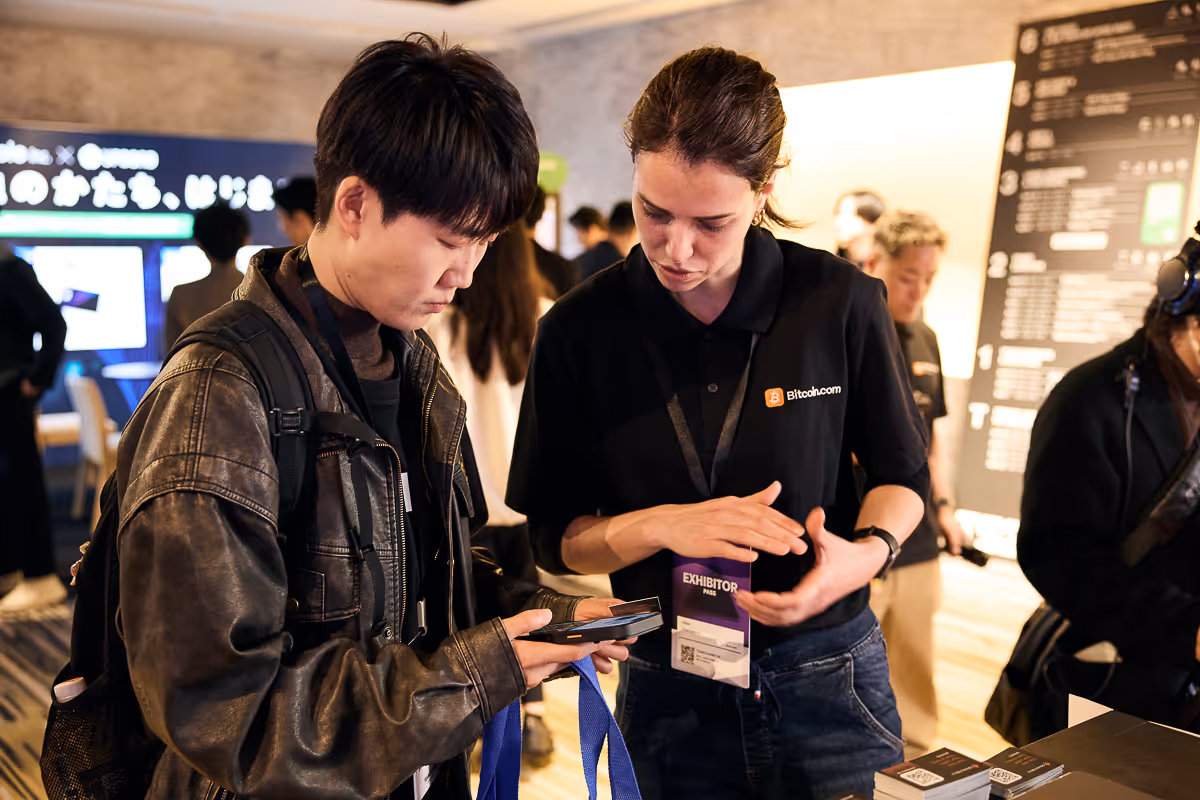 展示会の参加者がスマホの操作を説明者と相談している様子。