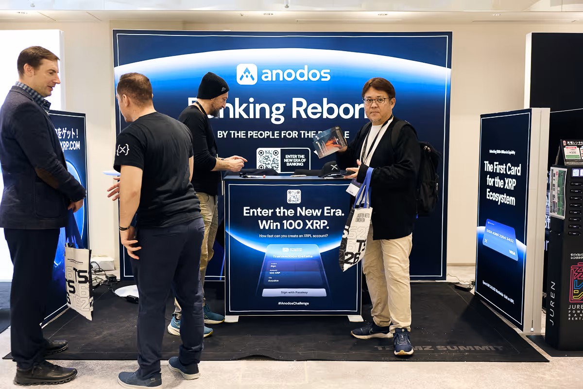 人々がAnodosのブースでXRPエコシステムの新時代に参加し、100 XRPを獲得するプロモーションに関心を示している様子。