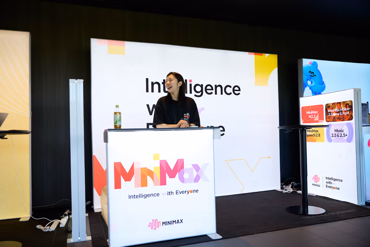 黒い服の女性がMinimaxのブースで笑顔で立っている様子。