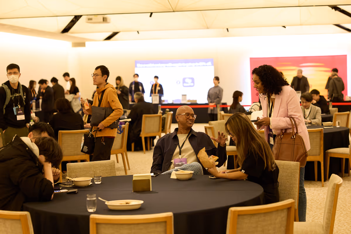 カンファレンス会場のテーブルで会話と休憩をしている人々。