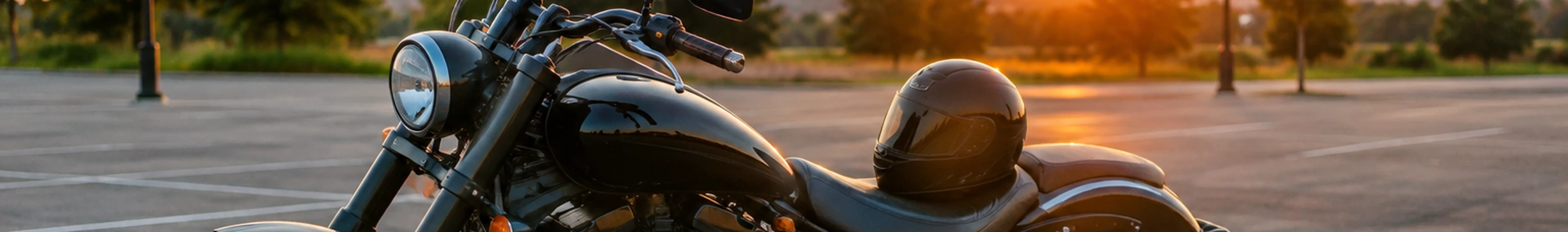 Black cruiser motorcycle with a helmet on the seat in an empty parking lot at sunset