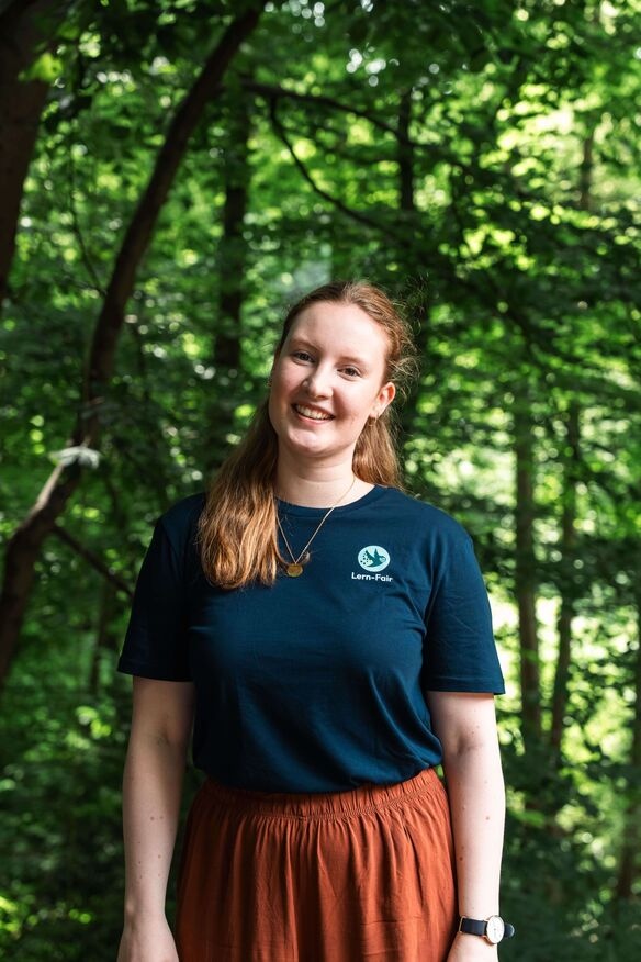 Junge Frau in Lern-Fair T-Shirt vor Wald