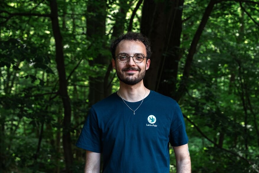 Junger Mann in Lern-Fair T-Shirt vor Wald