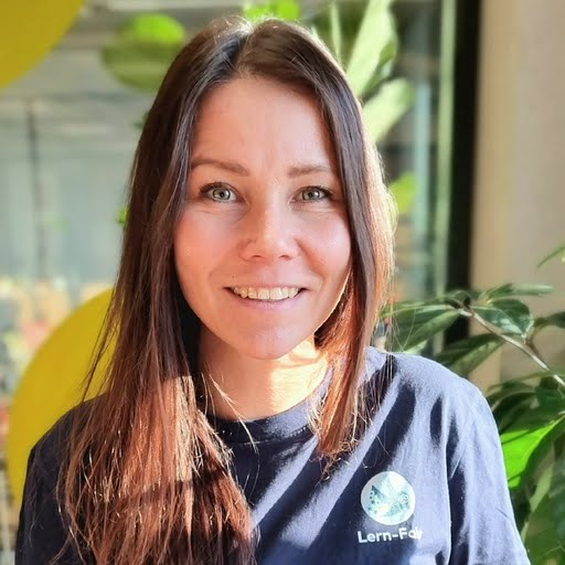 Junge Frau in Lern-Fair T-Shirt vor Wald mit Eulen Maskottchen