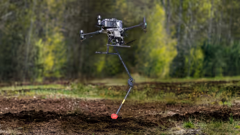 Researchers configuring a drone-mounted sensor system on a field worktable