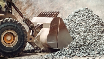 Wheel loader bucket beside a pile of crushed material isolated for inspection