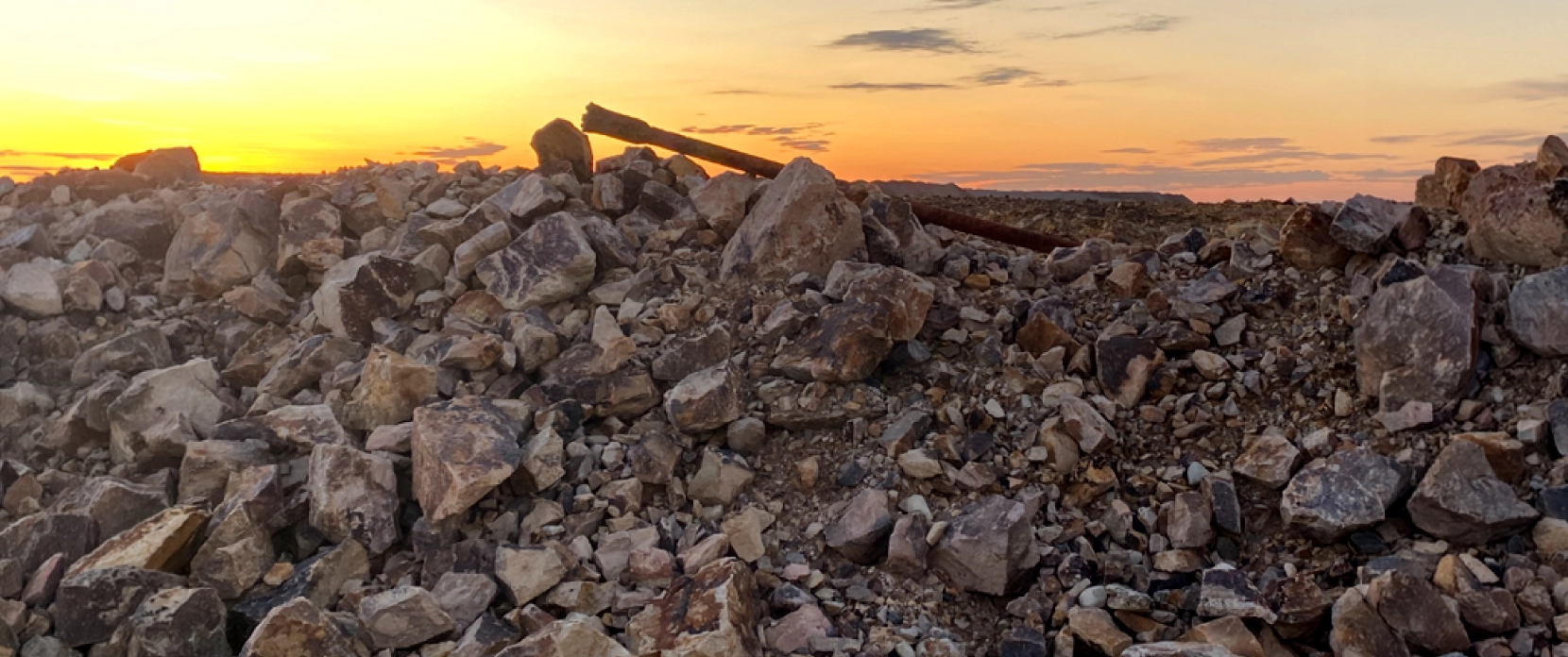 Lost drill rod lying among rocks on a mine stockpile