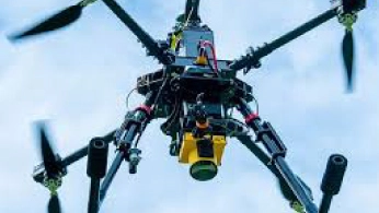 Researchers configuring a drone-mounted sensor system on a field worktable