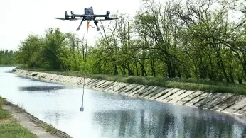 Researchers configuring a drone-mounted sensor system on a field worktable