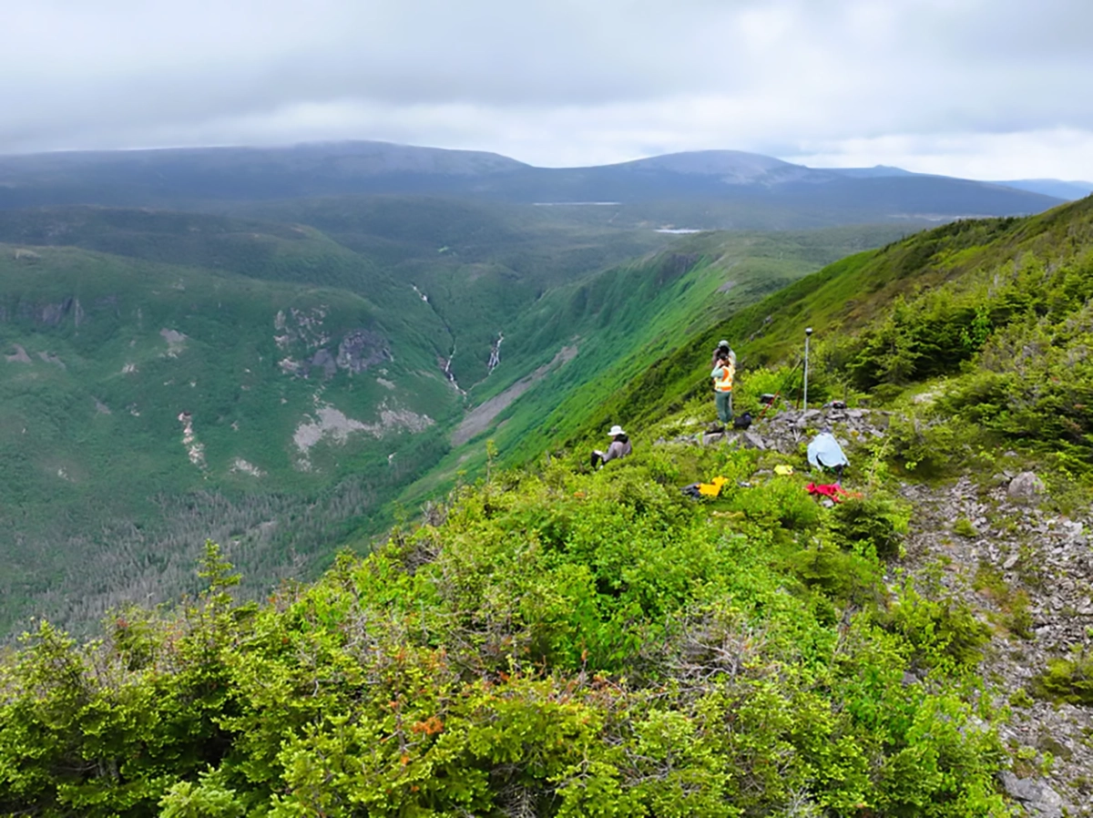 Field team preparing UAV survey equipment on a steep ridgeline in the Chic-Choc Mountains, illustrating the challenging alpine terrain.