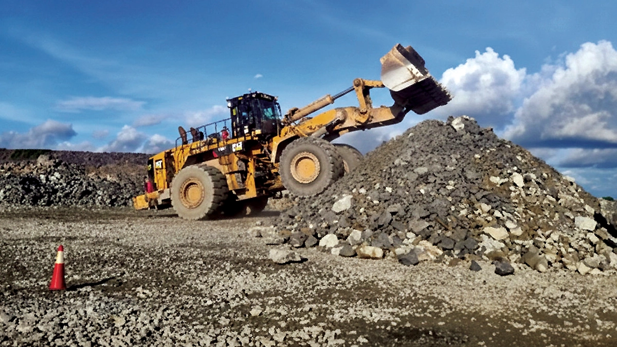 Large heavy-duty loader moving crushed rock at an open-pit mine to bury ferrous target objects at varying depths for the drone magnetometry detection test.