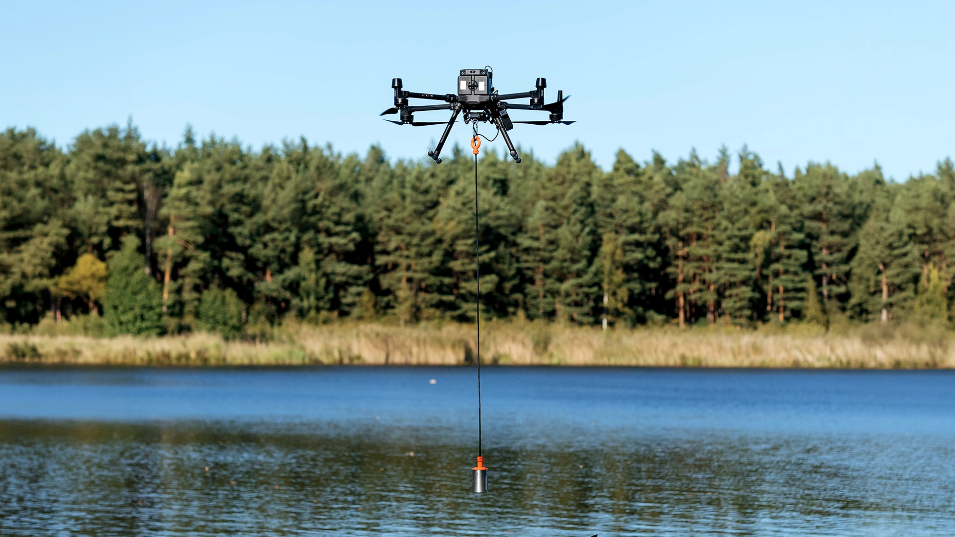 EchoLogger ECT 400S single-beam echo sounder suspended on a cable below a DJI Matrice drone over a lake