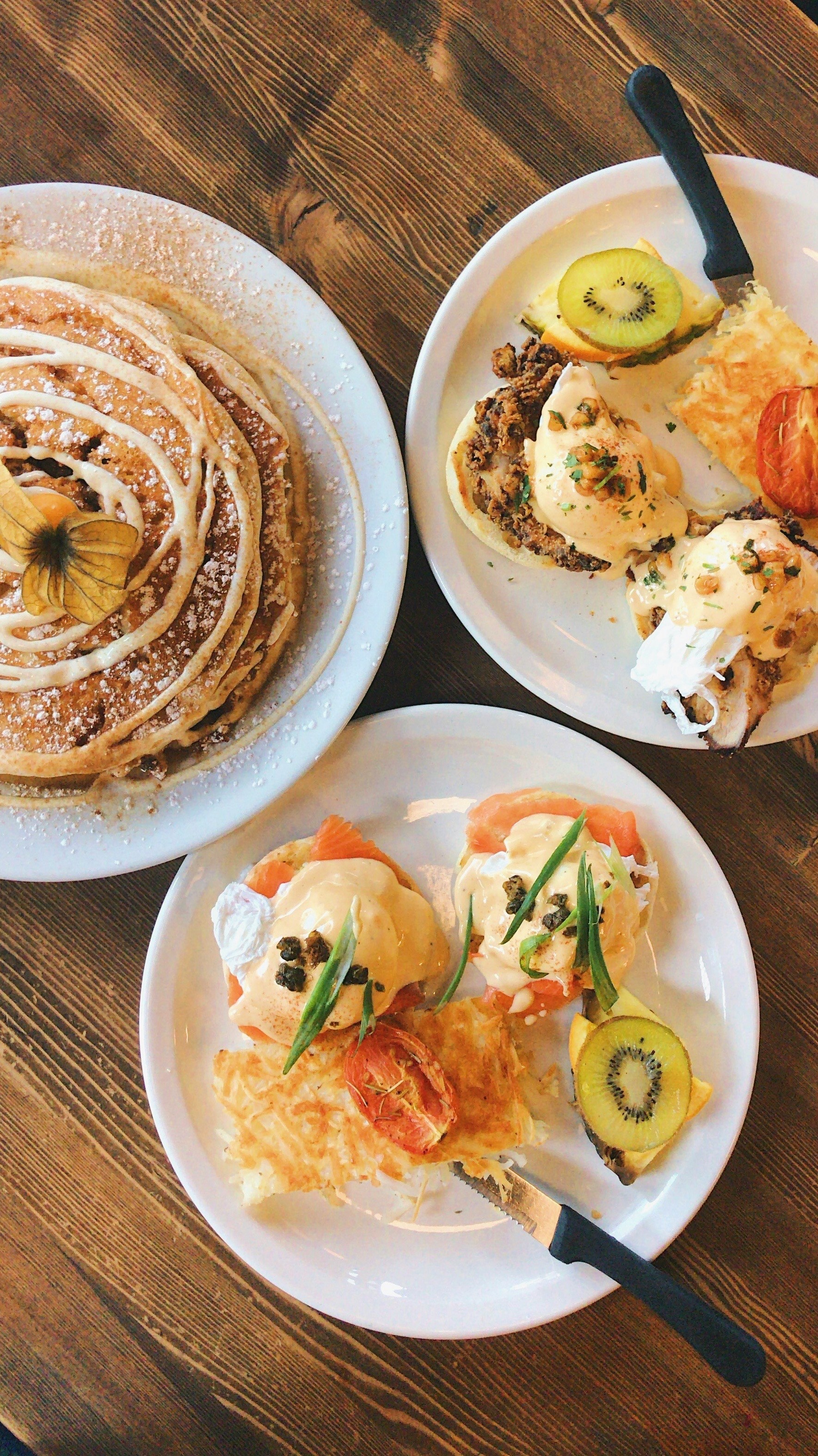 Cinnamon roll pancakes and eggs Benedict with smoked salmon and kiwi on a wooden table