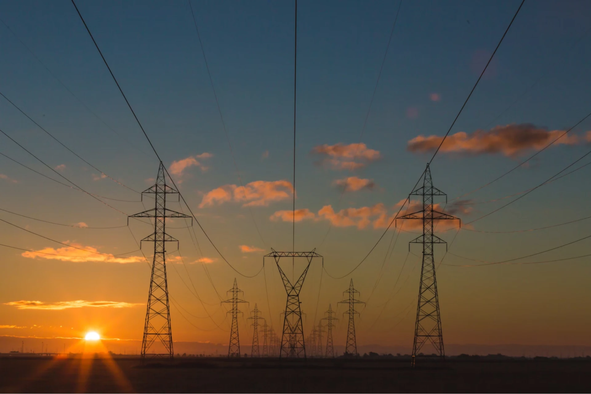 Hydro towers and power lines stretch into the horizon against a warm sunset and sky.