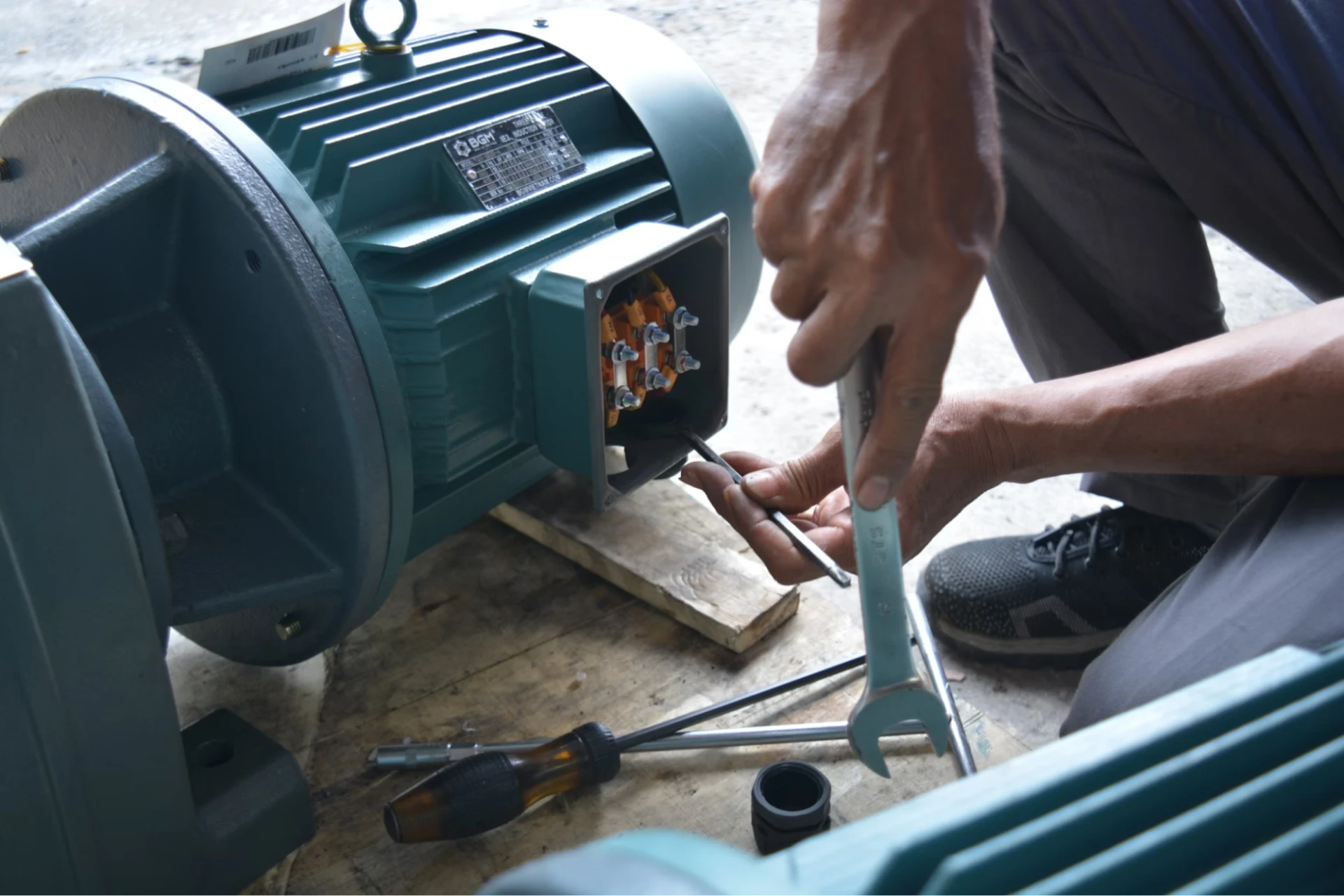 An HVAC technician holds a wrench with one hand, while inspecting machine screws with the other.