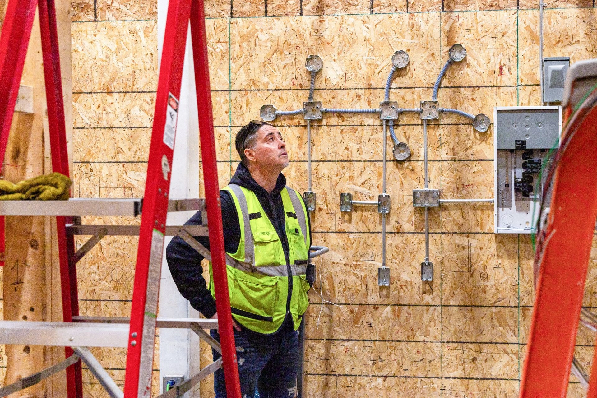 A man in a vest working on a raw electrical system