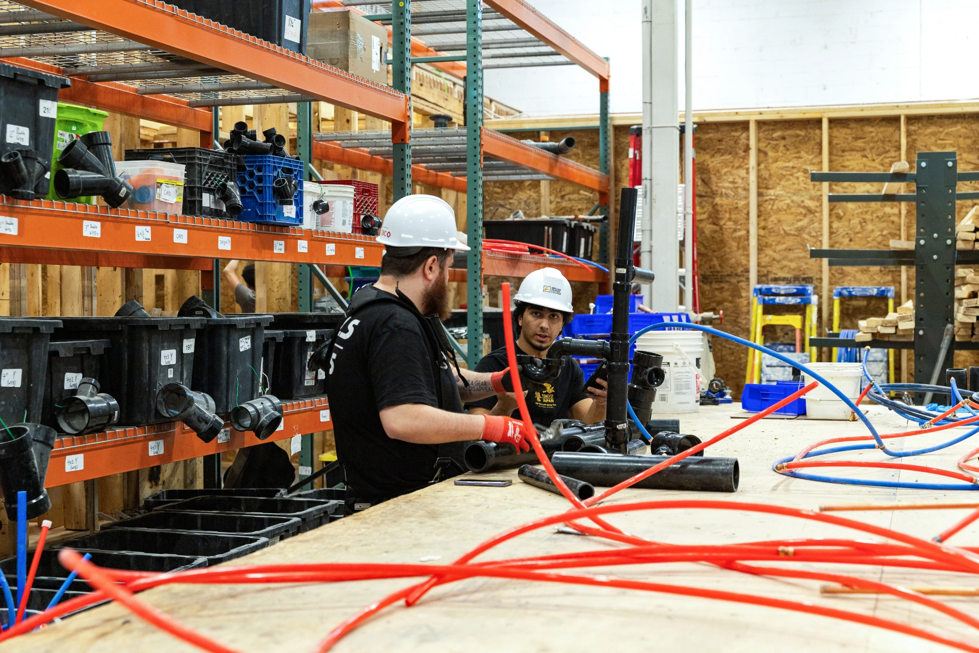 Two students working on pipes wearing hard hats 